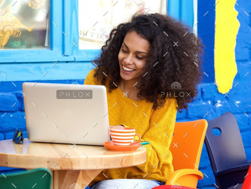 demo-attachment-29-happy-young-woman-sitting-at-outdoor-cafe-using-PFFBJ93
