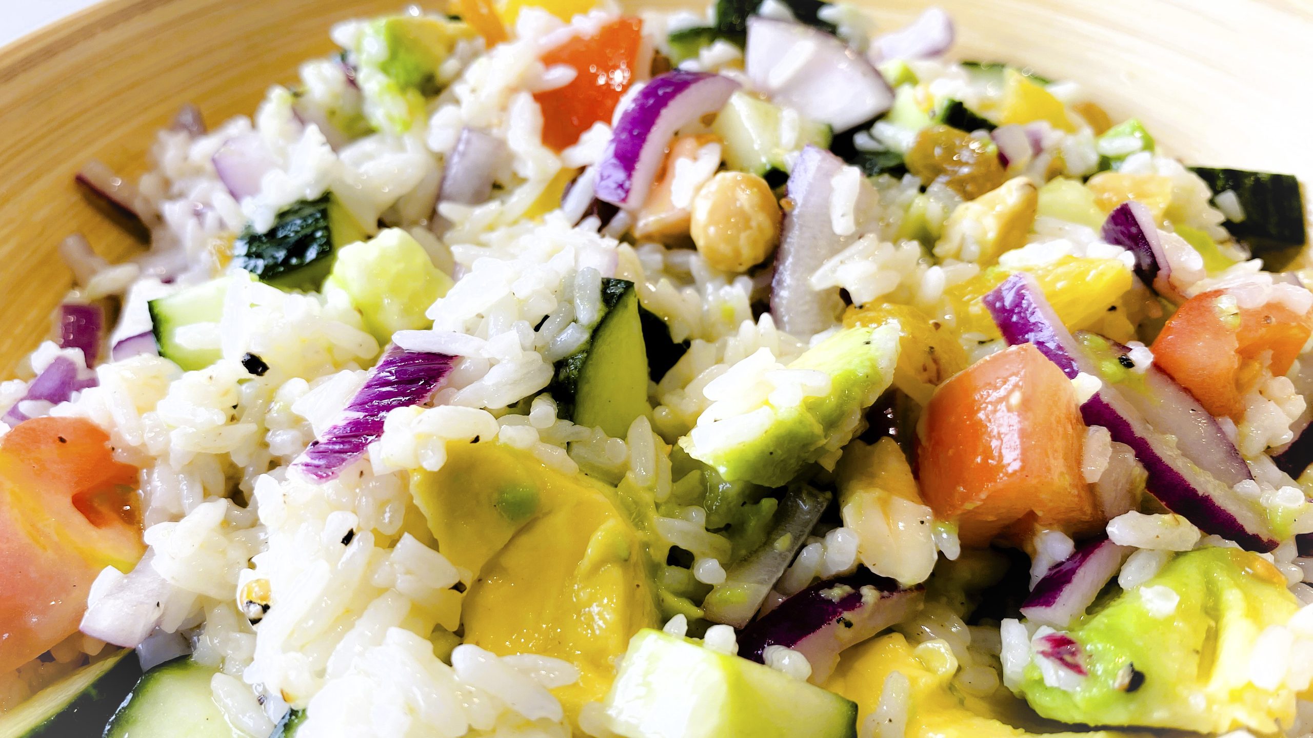 Sunlit Sovereign Rice Salad in a bowl with tomato, orange, avocado and nuts.